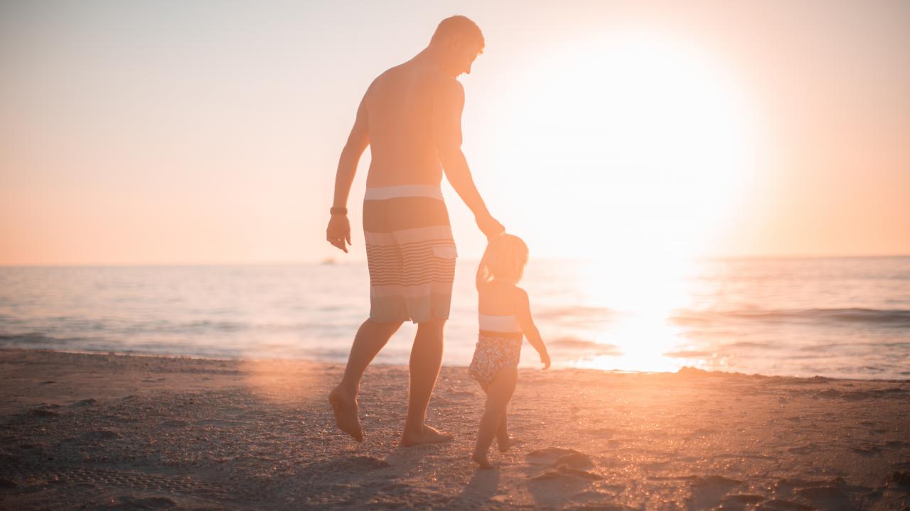 Parent and child walk towards water