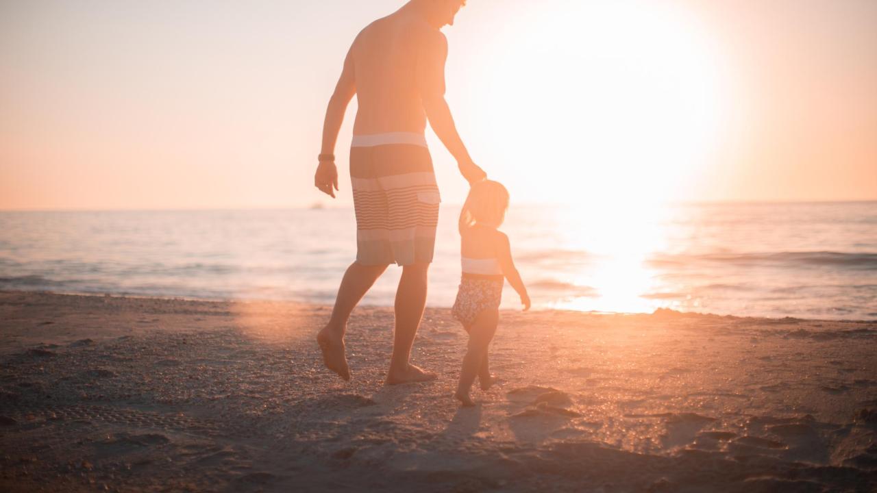 Parent and child walk towards water